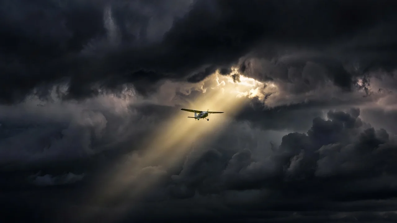 A small plane flying between dark stormy cloud layers